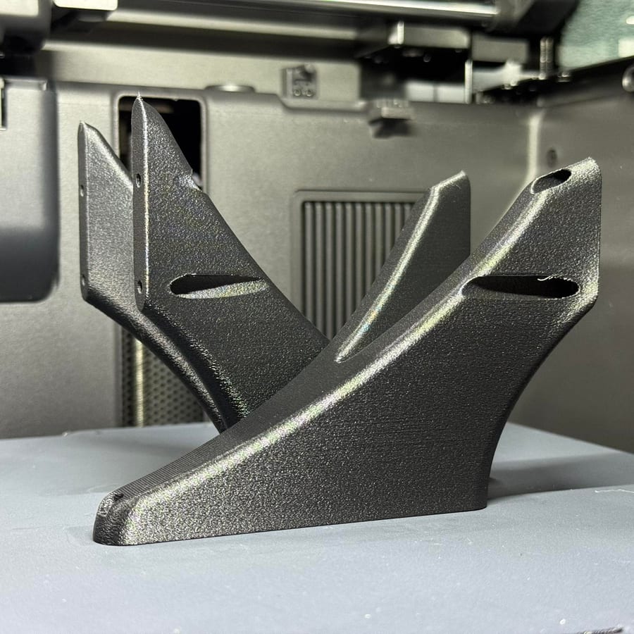 Black 3D printed angular bracket part on a print bed